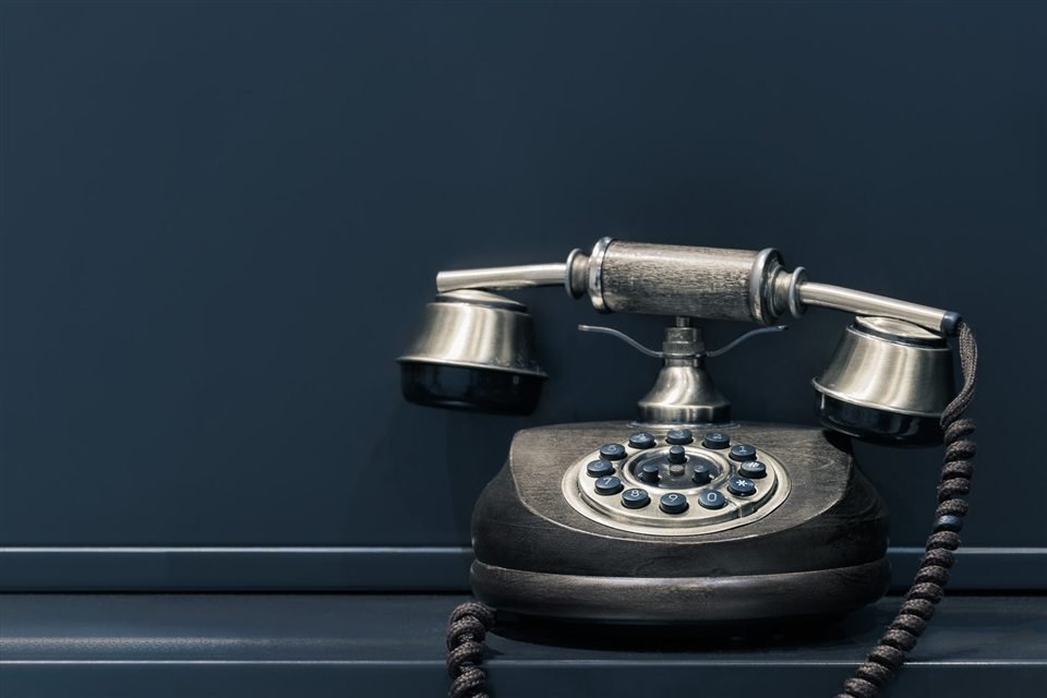 Teléfono de escritorio antiguo sobre un fondo azul